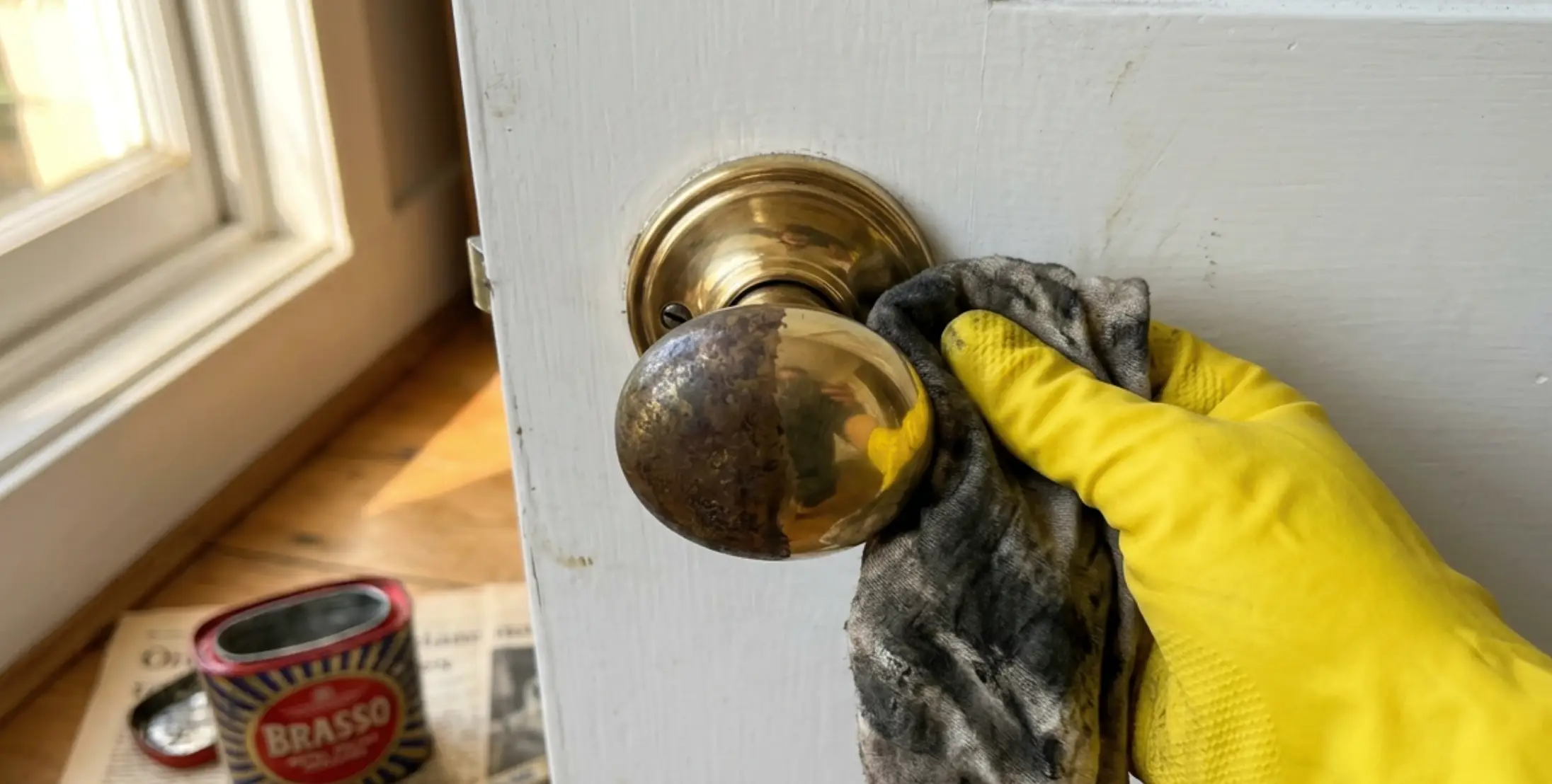 Heavily tarnished brass door handle being polished back to a shine